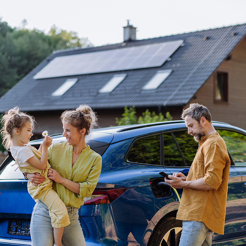 familie med elbil foran hus