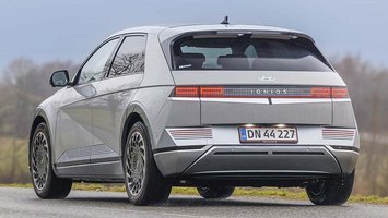 Hyundai Ioniq 5 set bagfra, mens den kører ud ad en landevej i gråvejr