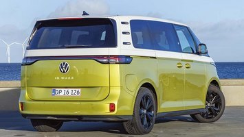 VW ID. Buzz set bagfra, mens den står på Amager Strandpark med vindmøller i baggrunden
