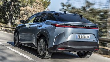 Lexus RZ set bagfra, mens den kører op ad bakke på en bjergvej
