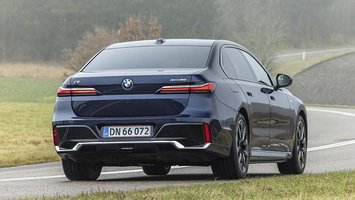 BMW i7 set bagfra, mens den køre på en snoet vej i tåge