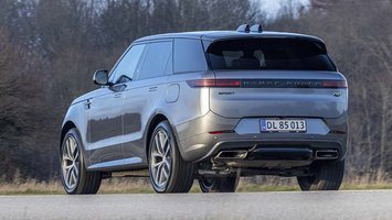 Range Rover Sport set bagfra, mens den kører på landevej med træer i baggrunden