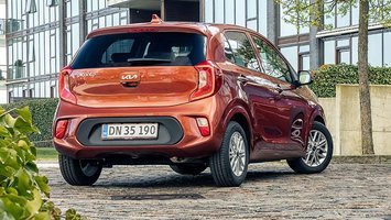 Kia Picanto set bagfra holder på brosten med grønt i forgrunden.