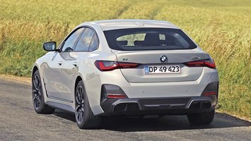 BMW i4 set bagfra, mens den kører på landevej med græs i baggrunden