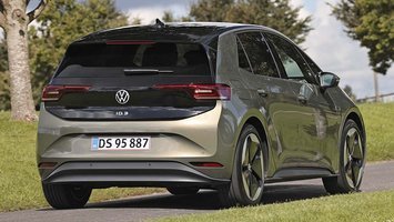 Elbilen VW ID.3 set bagfra, mens den kører på en landevej med græs og træer.