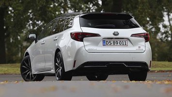 En hvid Toyota Corolla set bagfra, mens den holder foran træer
