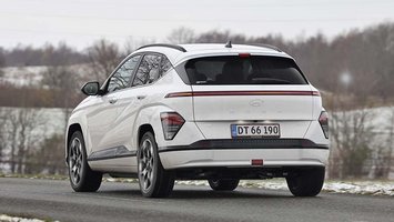 En hvid Hyundai Kona Electric set bagfra, mens den kører i snelandskab
