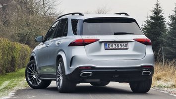 En sølvgrå Mercedes-Benz GLE set bagfra, mens den holder på en vej med en hæk i baggrunden.