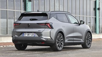 En mørkegrå Renault Scenic set bagfra, mens den holder foran en bygning med mange vinduer