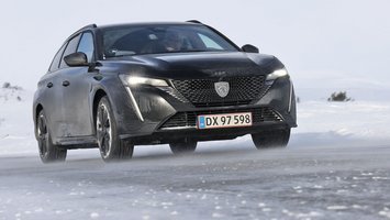 En mørk Peugeot E-308 set forfra kører på en snedækket vej