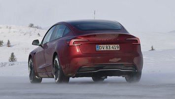 Rød Tesla Model 3 set bagfra kører i snelandskab
