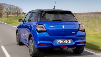 En blå Suzuki Swift set bagfra, mens den kører på vej