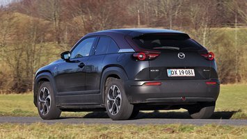 Sort Mazda MX-30 set bagfra kører på en vej
