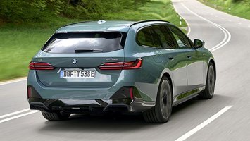Grøn BMW i5 Touring set bagfra, mens den kører på vej