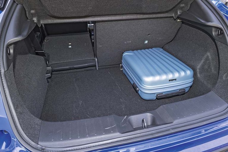 Bagagerummet i enNissan Juke med en blå kuffert og det ene bagsæde lagt ned.