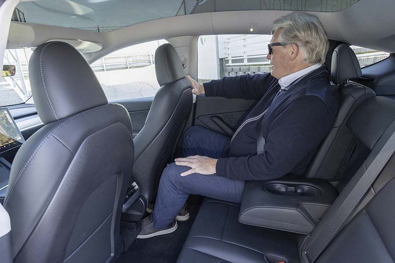 Mand sidder på bagsædet af en Tesla Model Y