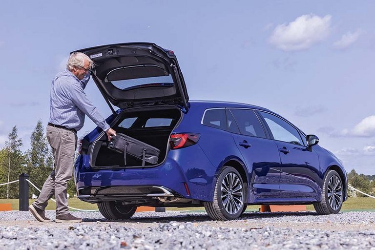 Mand står ved bagagerum på en Toyota Corolla Touring Sports