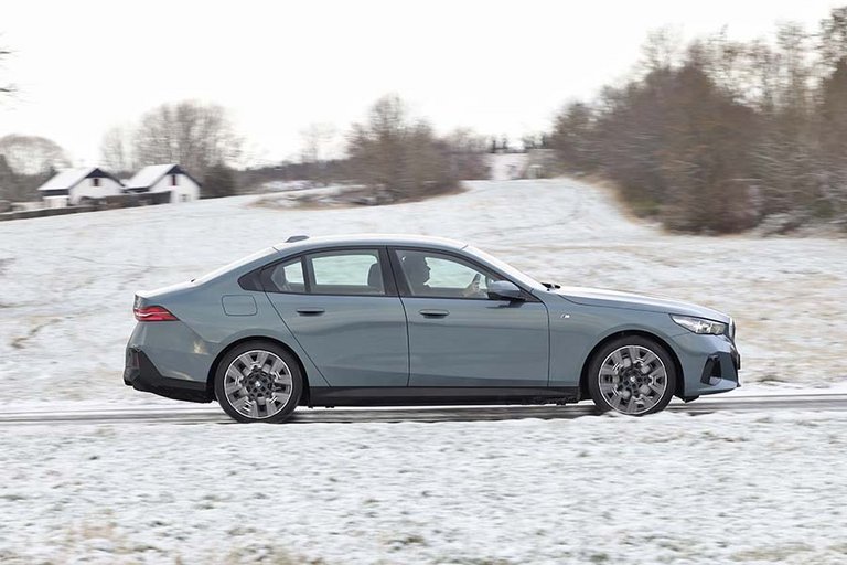 BMW i5 set fra siden, mens den kører på en snedækket vej