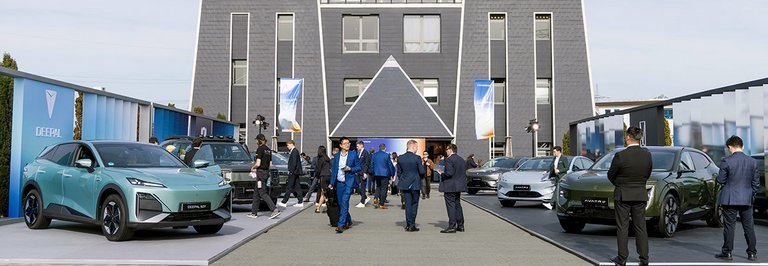 Biler og folk foran pyramide.