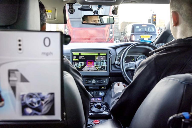 KOntrolperson sidder på forsædet af en selvkørende Nissan Leaf.