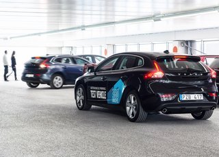 Forsøgsbilen kører fint rundt på en stor parkeringsplads med ni km i timen, mens den passer på andre biler og fodgængere og leder efter en ledig bås.