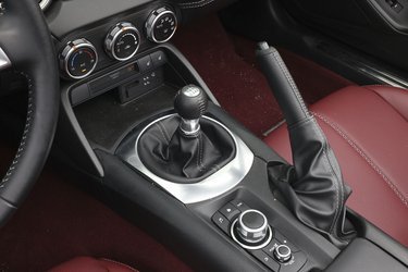 En af det helt store glæder i MX-5 er gearskiftet. Det er en sand fornøjelse, fordi det går let samtidig med, at der er en mekanisk fornemmelse i selve skiftet. Den runde, sølvfarvede knap benyttes til at styre info-skærmen.