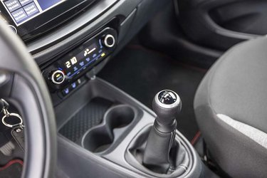 Der er fem gear i bilen, og der er gode fralægningsmuligheder foran gearstangen. Bemærk det digitalt indstillelige klimaanlæg.