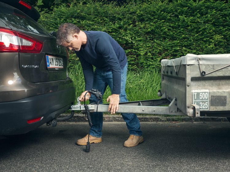 Mand kobler trailer til sin bil. 