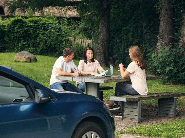 Familie på ferie har parkeret bilen og tager en pause på rasteplads. 