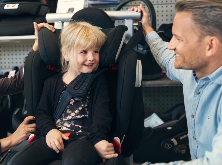Barn prøver at sidde i en autostol i en butik inden køb. 