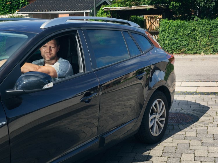 Mand holder i sin bil og kigger ud af vinduet. 