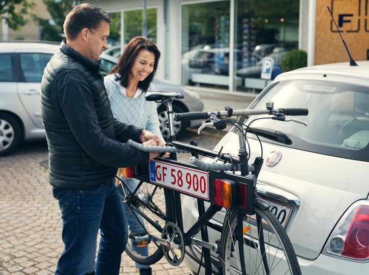 Mand og kvinde er ved montere lygtebom på en bil. 