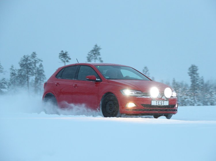 Rød bil kører på vej fyldt med sne. 