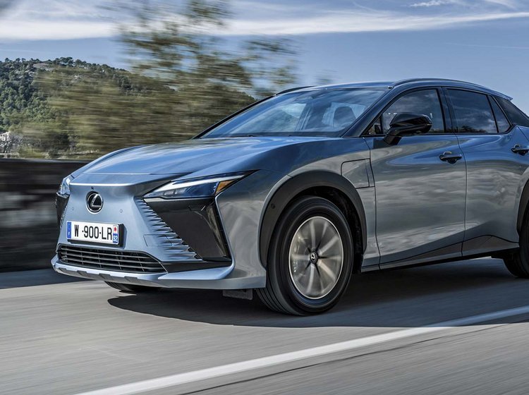 En Lexus RZ kører på bjergvej med udsigt til havet i baggrunden