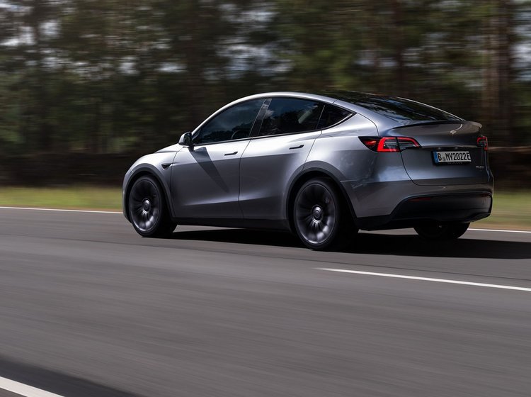 En grå Tesla Model Y kører på en vej. 