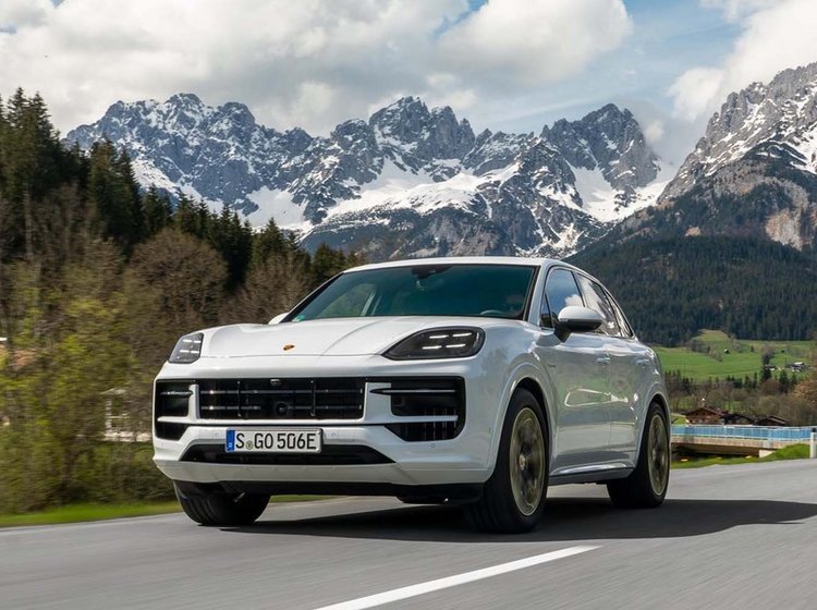 HVis Porsche Cayenne i fart på landevej med bjerge i baggrunden