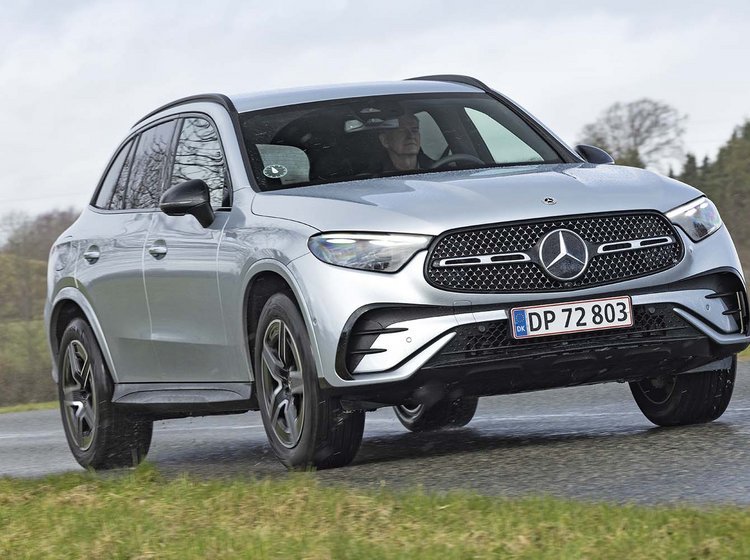 En sølvgrå Mercedes GLC kører på en landevej med skov i baggrunden