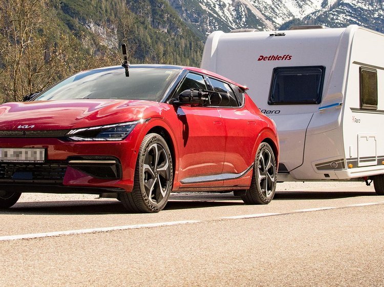 Kia EV6 trækker en campingvogn i bjergene. 