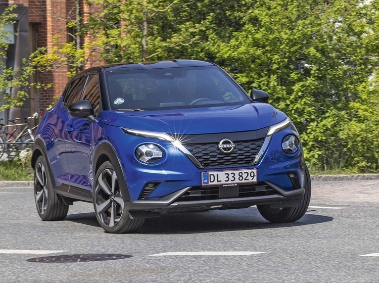 En blå Nissan Juke drejer ud på en asfaltvej