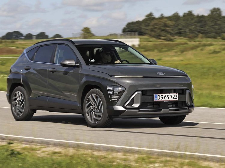 Hyundai Kona kører på landevej med græs i baggrunden.