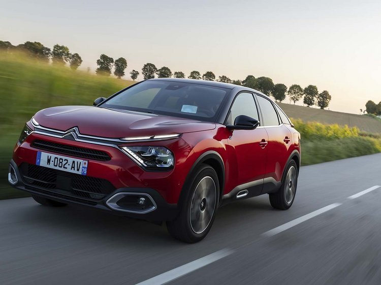 Citroën Ë-C4 kører i et sving på en landevej ved solnedgang.