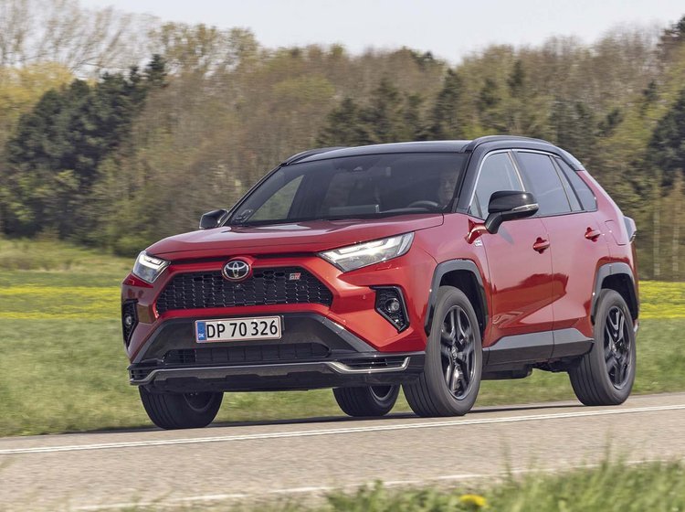 En rød Toyota RAV4 kører på en landevej med træer i baggrunden