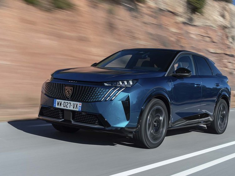 En Peugeot E-3008 elbil set forfra, mens den kører på en bjergvej med klipper i baggrunden