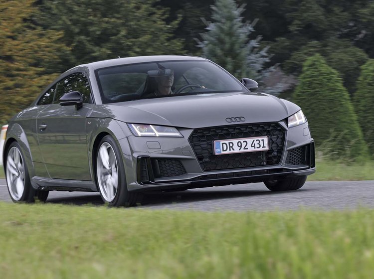 En Audi TT kører på en landevej med græs i forgrunden og træer i baggrunden