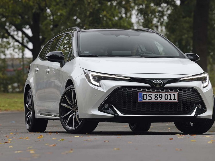 En hvid Toyota Corolla set forfra, mens den holder foran træer