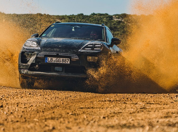 Porsche Macan forfra med sand, der flyver op fra hjulene.