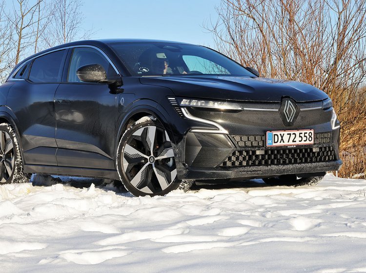 En sort Renault Megane holder i sne med buske i baggrunden