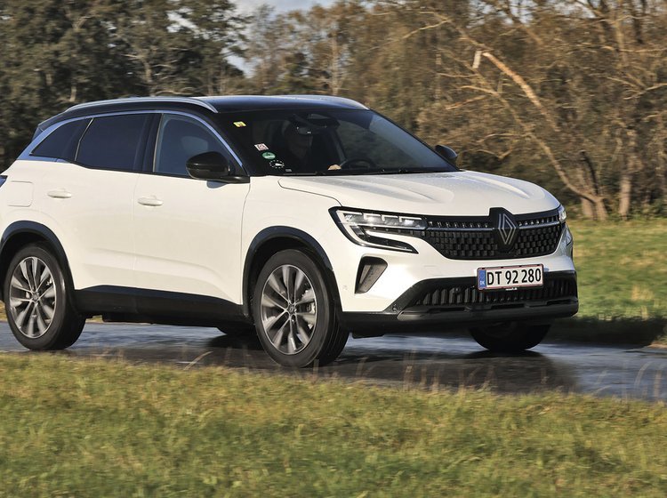 En hvid Renault Austral kører på en landevej med træer i baggrunden