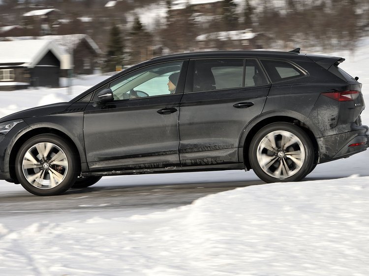 En Skoda Enyaq elbil set fra siden kører på en snedækket vej