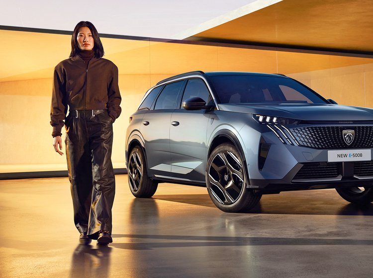 Peugeot 5008 forfra med person i forgrunden.